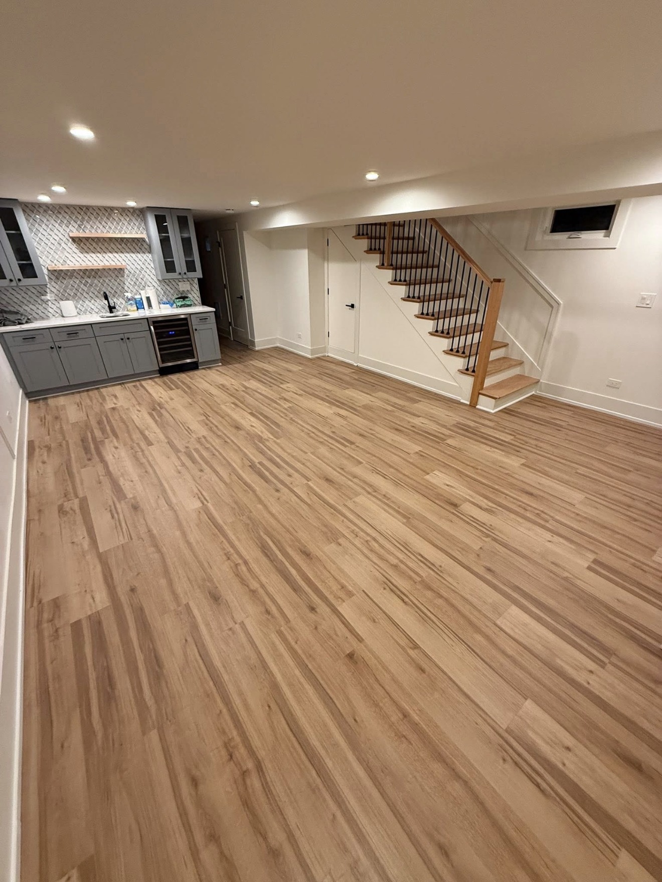 Finished basement with new LVP flooring, wet bar, and staircase